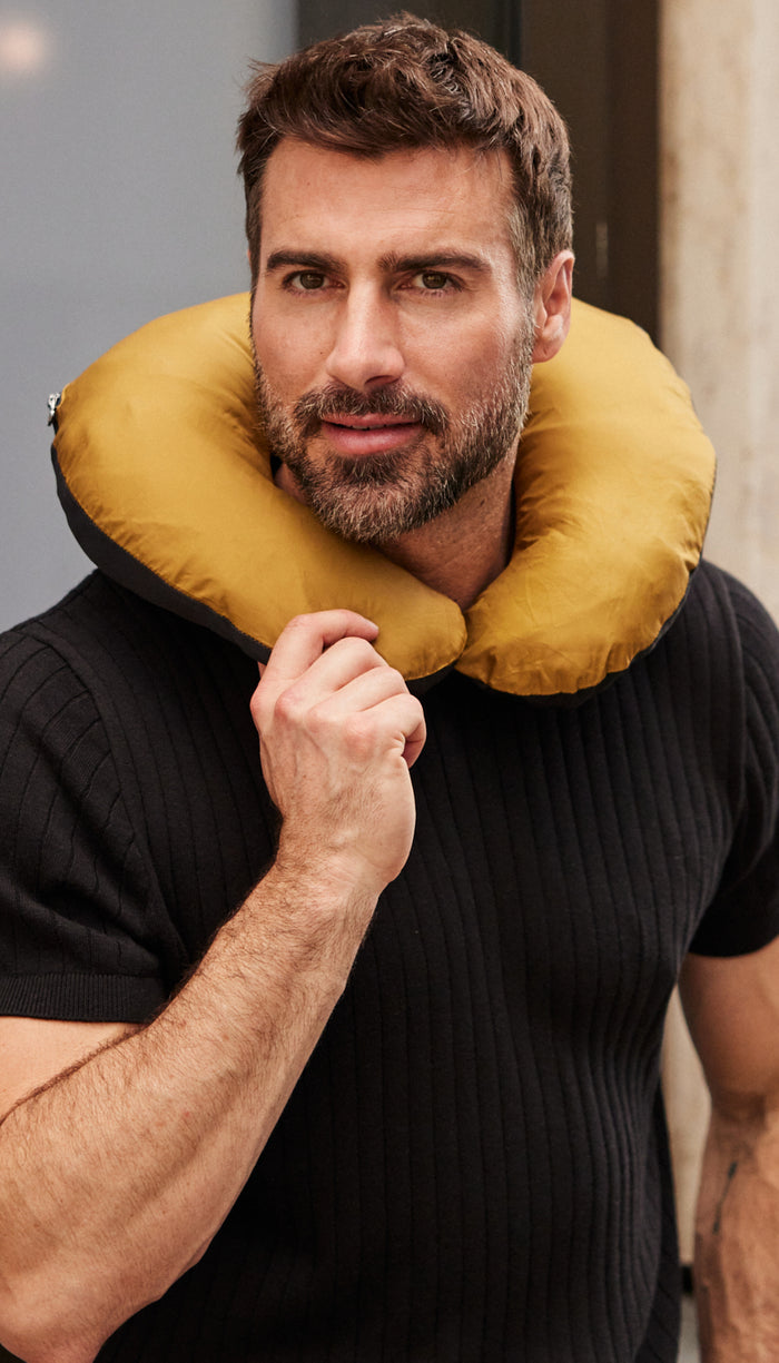 a man wearing a yellow neck pillow